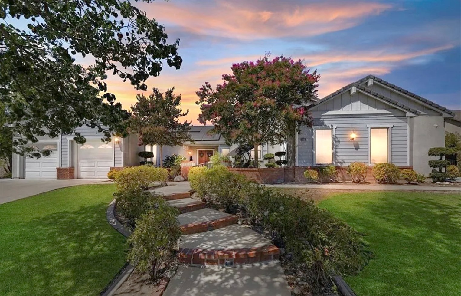 The front of Abundant Living Estates, a single-story home with a landscaped brick walkway and lawn
