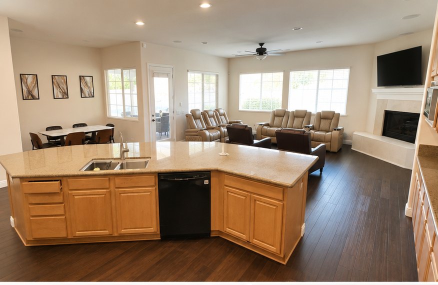 Open kitchen island looking onto a great room with recliners and a fireplace