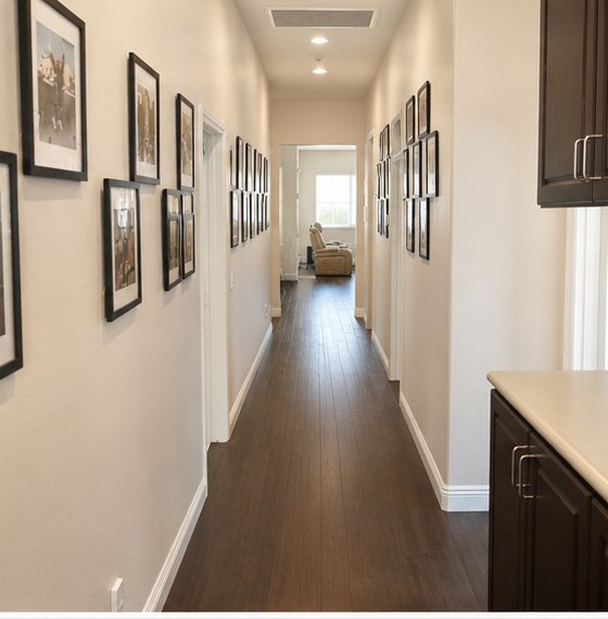 Wide hallway lined with framed photographs leading to the bedrooms