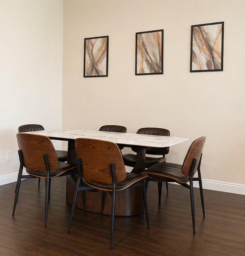 Small dining table with four chairs beneath three framed prints